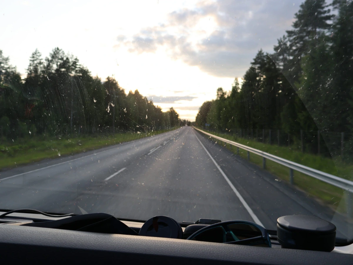 Näkymä raskaan ajoneuvon ohjaamosta maantielle hämärän aikaan. Kuva havainnollistaa havainnointia ja ennakoivaa ajamista ammattiliikenteessä.